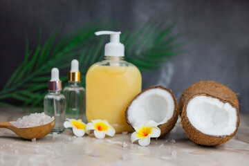 Fototapeta na wymiar liquid soap dispenser with palm leaf with sea salt and mango flower