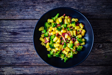Gnocchi with bacon and broccoli on wooden table
