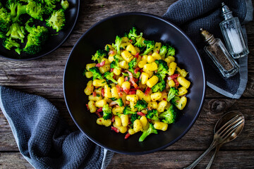 Gnocchi with bacon and broccoli on wooden table
