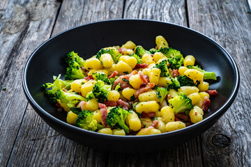 Gnocchi with bacon and broccoli on wooden table
