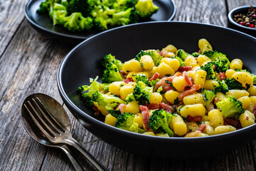 Gnocchi with bacon and broccoli on wooden table
