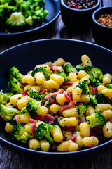 Gnocchi with bacon and broccoli on wooden table
