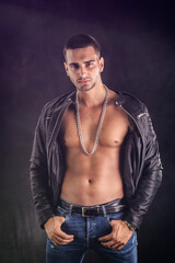 Handsome young man wearing leather jacket on naked torso