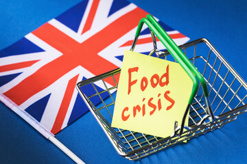 British flag and note with text in empty food basket on colored background, UK food crisis concept