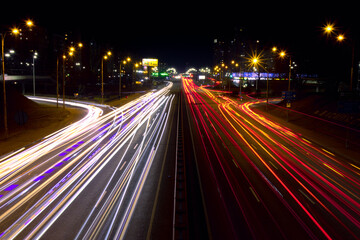 Fototapeta na wymiar Light trails from fast moving cars at night. Cars move fast on a wide road