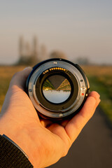 camera lens held by hand infront of street landscape