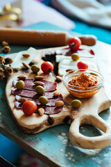 Fototapeta premium Fried dough called Ustipci with olives, paprika cream called ajvar and meat served on a wooden board. Bosnian or Serbian traditional food