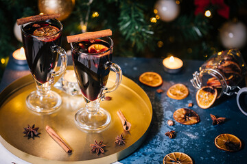 Mulled wine with cinnamon, anise star and orange served in festive Christmas decoration in front of a Christmas tree and lights. Ideal drink for advent and celebration.