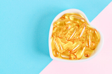 Fish oil capsules in cup on beautiful background