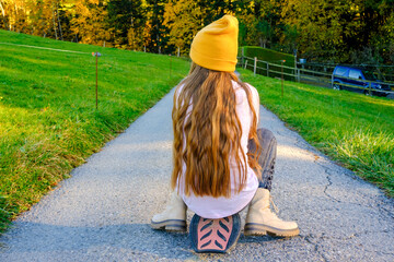 Teenager Mädchen fährt auf Wave-Board sitzend einen Berg hinunter.