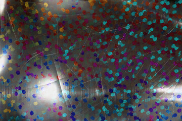 detail macro photo of silver rainbow holographic dot foil material with bright light leaks and...