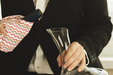 sommelier pours wine into decanter at a table in a restaurant