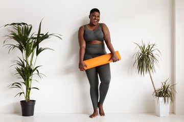 Pretty african american chubby woman posing with fitness mat - obrazy, fototapety, plakaty