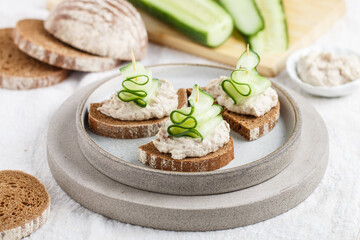 Delicious appetizer of rye bread with herring forshmak and cucumber. Canapes for a party. Christmas and New Year snacks in the form of Christmas trees. Selective focus - 474529555