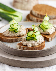 Delicious appetizer of rye bread with herring forshmak and cucumber. Canapes for a party. Christmas and New Year snacks in the form of Christmas trees. Selective focus