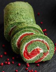 Sliced spinach roll with salted (smoked) red fish (salmon, trout) and cream cheese (ricotta) close-up. roulade.  A festive snack for gourmets. Christmas. New Year. Selective focus