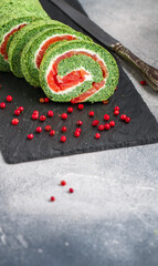 Sliced spinach roll with salted (smoked) red fish (salmon, trout) and cream cheese (ricotta) close-up. roulade.  A festive snack for gourmets. Christmas. New Year. Selective focus, copy space