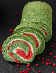 Sliced spinach roll with salted (smoked) red fish (salmon, trout) and cream cheese (ricotta) close-up. roulade.  A festive snack for gourmets. Christmas. New Year. Selective focus
