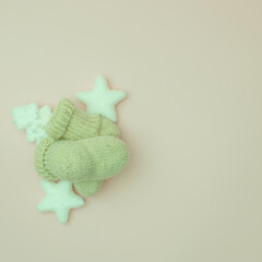 Baby wool socks with Christmas and New Year decorations on pastel background. Creative layout. Holiday flat lay concept.