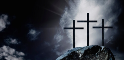 Silhouette of three crosses on a rocky hill against dramatic sky background as symbol of the Crucifixion and resurrection of Jesus Christ. Copy space.
