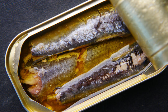 open tin of sardines on white tiles background.