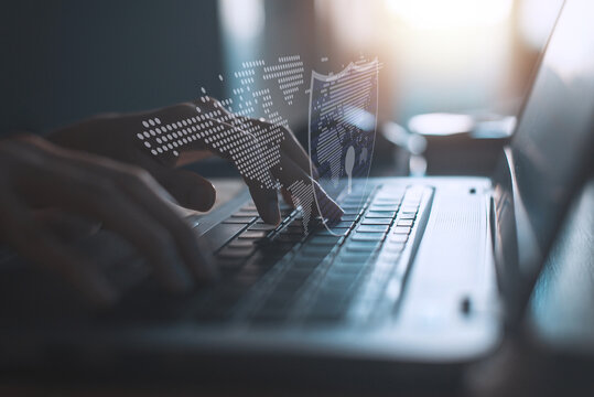 Hacker in black hoodie using laptop on the desk to hacking system with binary code and upload the malware with virtual screen display binary code, bar graph and world maps on the background