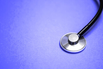 Very Peri trend color of the year 2022. Close up black modern stethoscope with reflection on blue background with copy free space for message. Medical nurse or doctor equipment. Medicine healthcare 