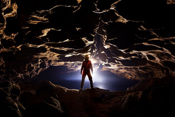 Speleologist in a cave in the rays of light