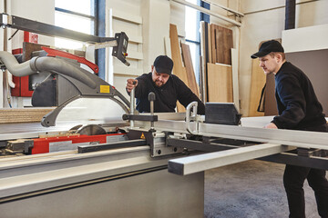Sawing up of a wooden board on a sliding table saw. Woodworking and carpentry production. Furniture...