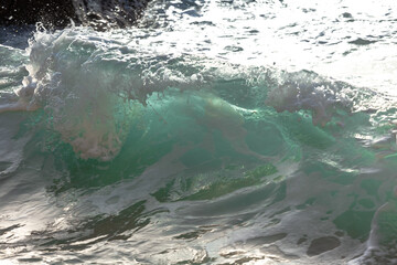 The rays illuminate the sea wave in turquoise, close-up.
