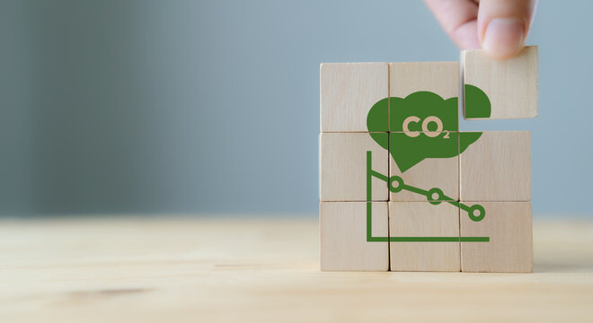 CO2 emission concept. Green industries business concept. Net zero emissions. Renewable energy, sustainable technology, ecology solutions. Hand puts the wooden cubes with CO2 emission reduction icon.