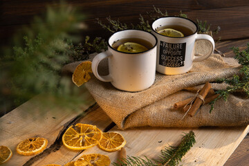 Obraz na płótnie Canvas a cup of hot tea on a wooden table against a background of greens and pine needles
