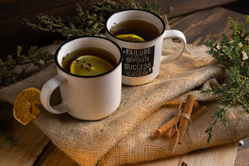 a cup of hot tea on a wooden table against a background of greens and pine needles