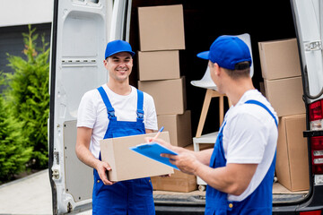 Two removal company workers unloading boxes from minibus into new home