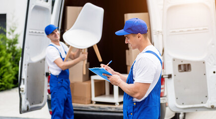 Two removal company workers unloading boxes from minibus into new home