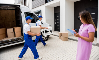 Two removal company workers unloading boxes from minibus into customer's home