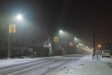 Prowincjonalne miasteczko w zimową śnieżną noc. - obrazy, fototapety, plakaty