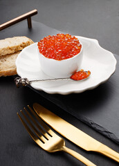 Red caviar in a bowl with ice and a glass of champagne on a tray. Christmas and New Year background