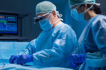 Multiracial team of professional medical surgeons performs the surgical operation in a modern...