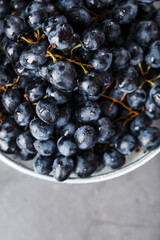 Sweet black grapes in a metal bowl on a dark textured background.