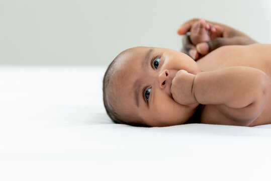 Portrait images of African girl baby newborn is 3-mount-old, lying and smile with happy on white bed, to African child and baby newborn concept.