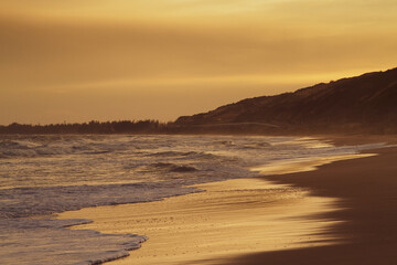 Empty beach of ocean beach at gold sunset.
