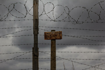 An old barbed wire fence with signs enclosing a restricted area.