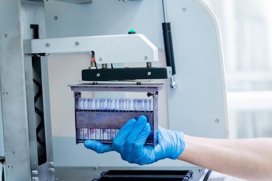 Laboratory assistant works with automatic multi slides stainer at the modern laboratory.