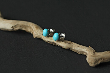 Stud earrings made of natural turquoise sleeping beauty. Designer earrings from natural turquoise stones. Women's jewelry on a black background and wood. Author's modern jewelry