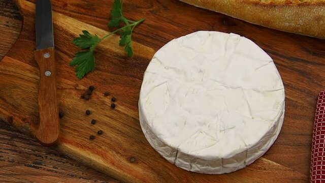 camembert avec couteau, &eacute;pices et pain sur planche de bois