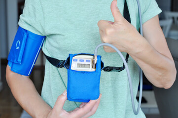 Woman wearing holter monitor device for daily monitoring of an electrocardiogram. Health care and disease prevention.the Patient shows the result 