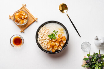 Traditional Chicken Porridge rice gruel in bowl shot on white background with negative space.
