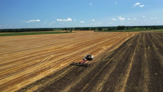 The tractor works the soil after the harvest aerial view