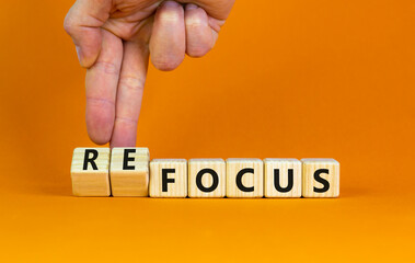 Focus or refocus symbol. Businessman turns wooden cubes and changes the word focus to refocus....